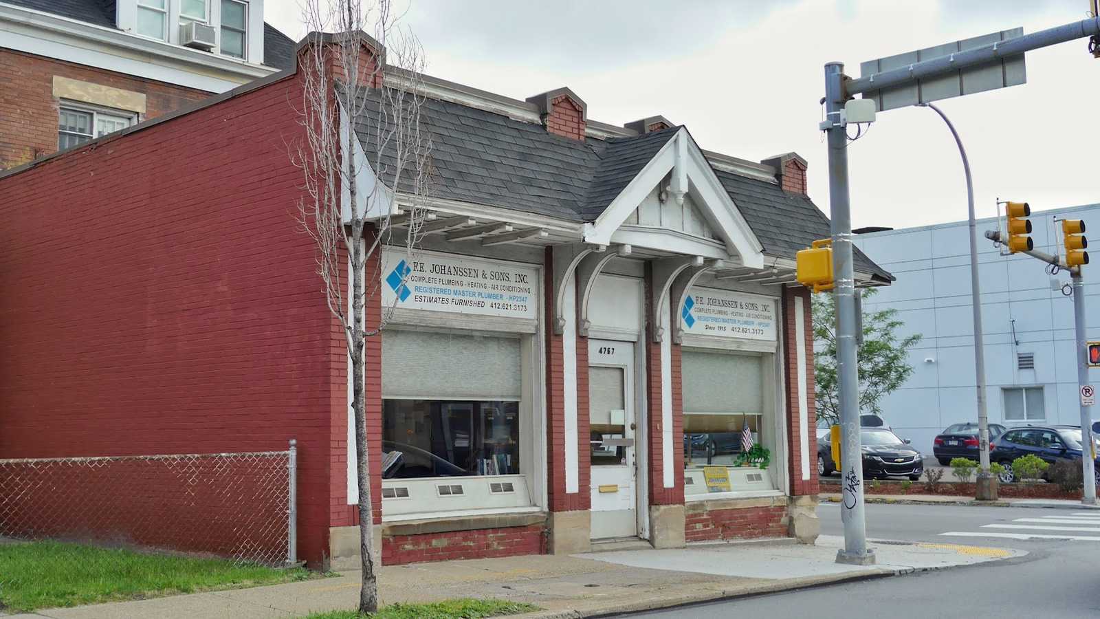 The red-brick F.E. Johanssen & Sons shop at 4767 Baum Boulevard, with painted window signs reading plumbing, heating and air conditioning.